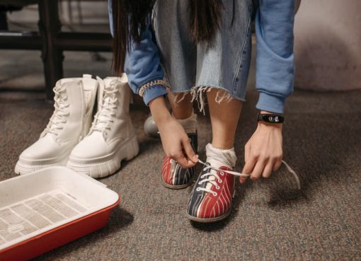 Close-up of a person tying bowling shoes, focused on footwear and hands indoors.